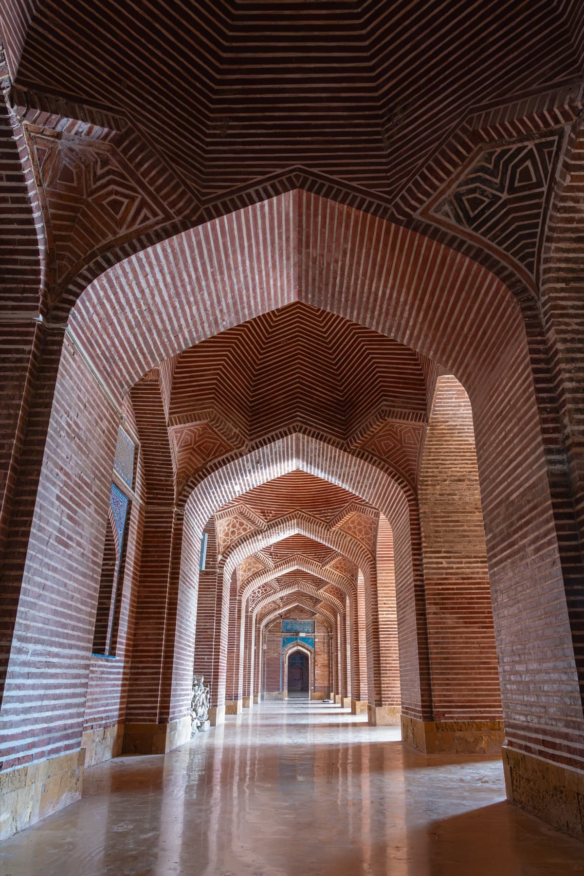 A long corridor of red brick arches